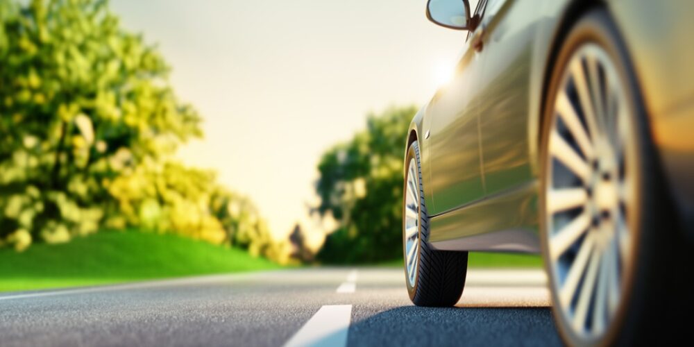 Car on sunny road with green landscape